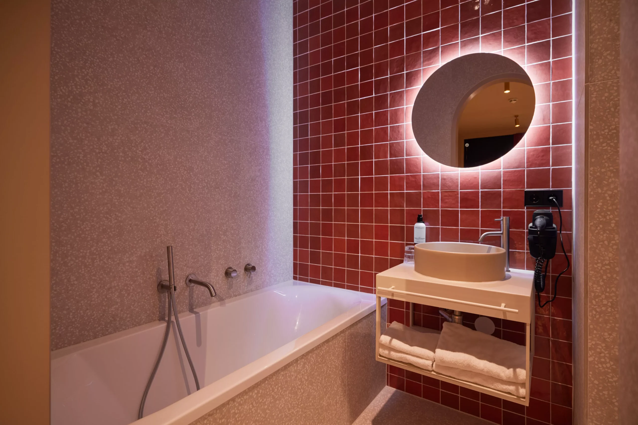 Badkamer van de Deluxe kamer met opvallende rode tegels en luxe wastafel in Heavens Hotel Hoorn