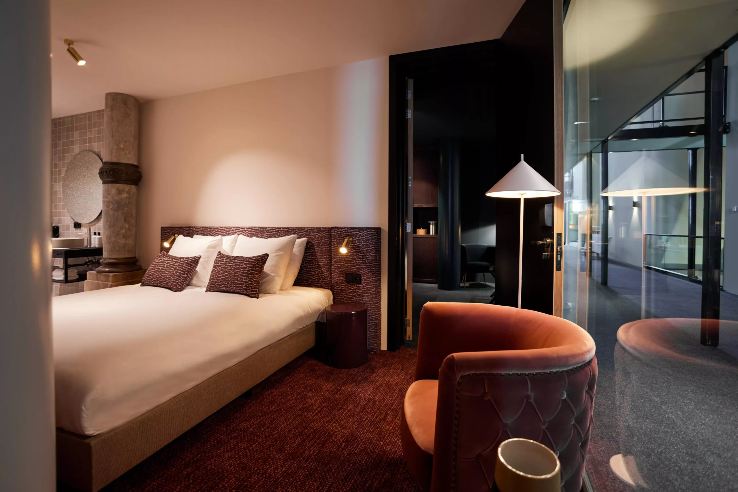 Stijlvolle Deluxe Room met designfauteuil, kolom en uitzicht op de gang in Heavens Hotel Hoorn