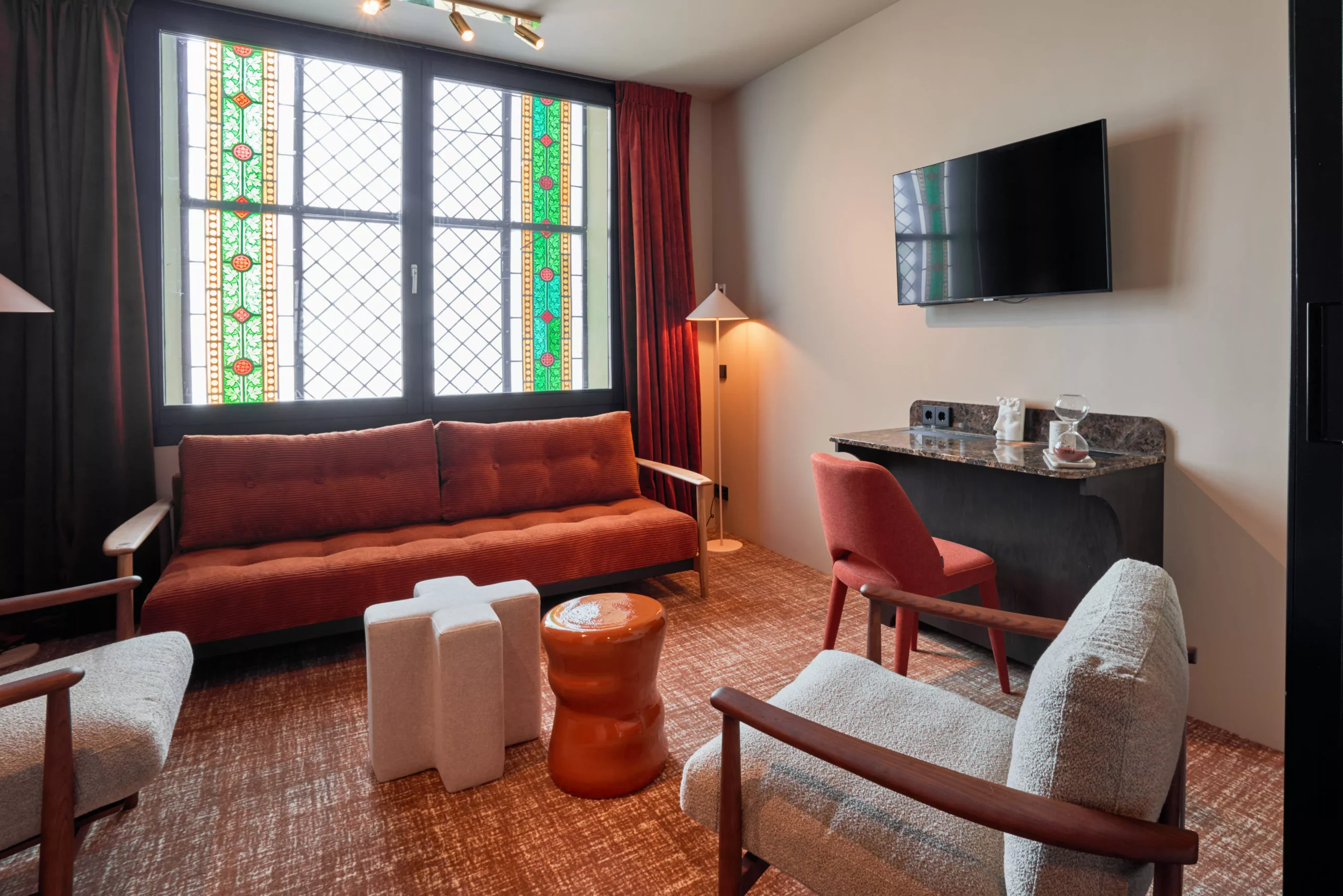 Zitkamer van de Family Suite met designmeubels en glas-in-loodramen in Heavens Hotel Hoorn